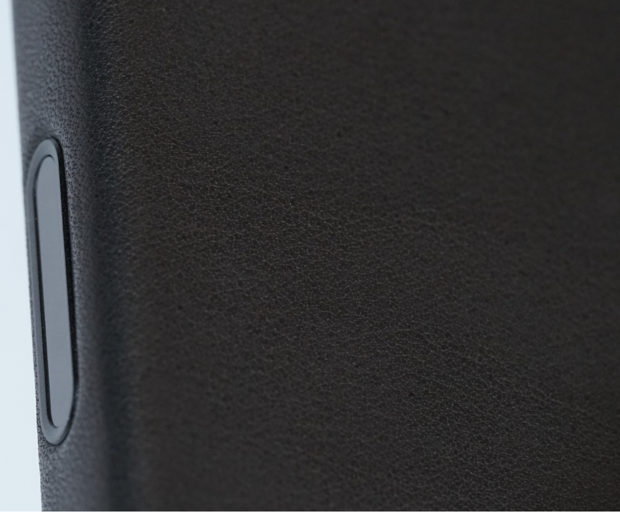 Close-up of a textured black phone case with a camera control button.