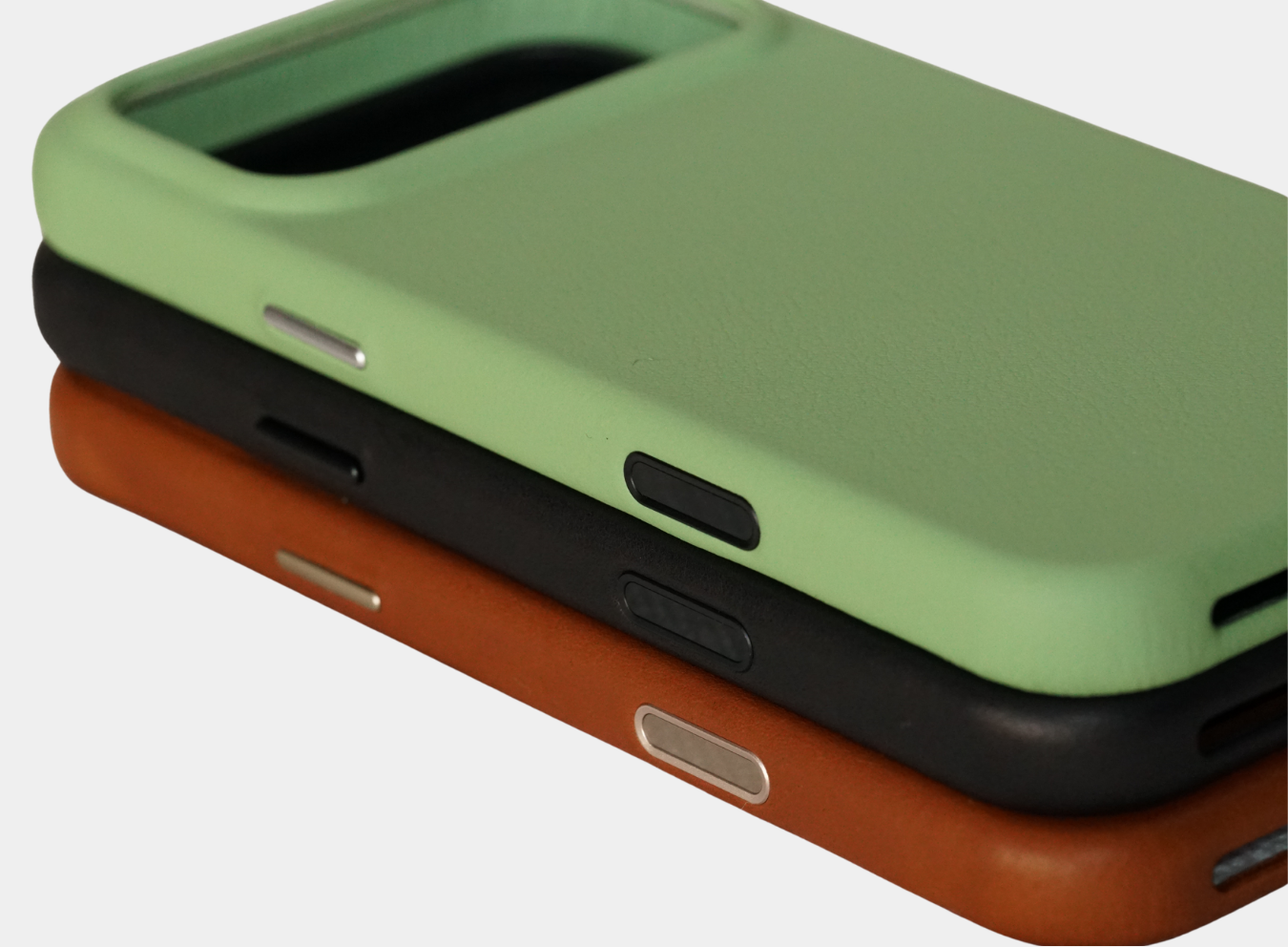three phone cases, one green, one black and one brown, on a white background