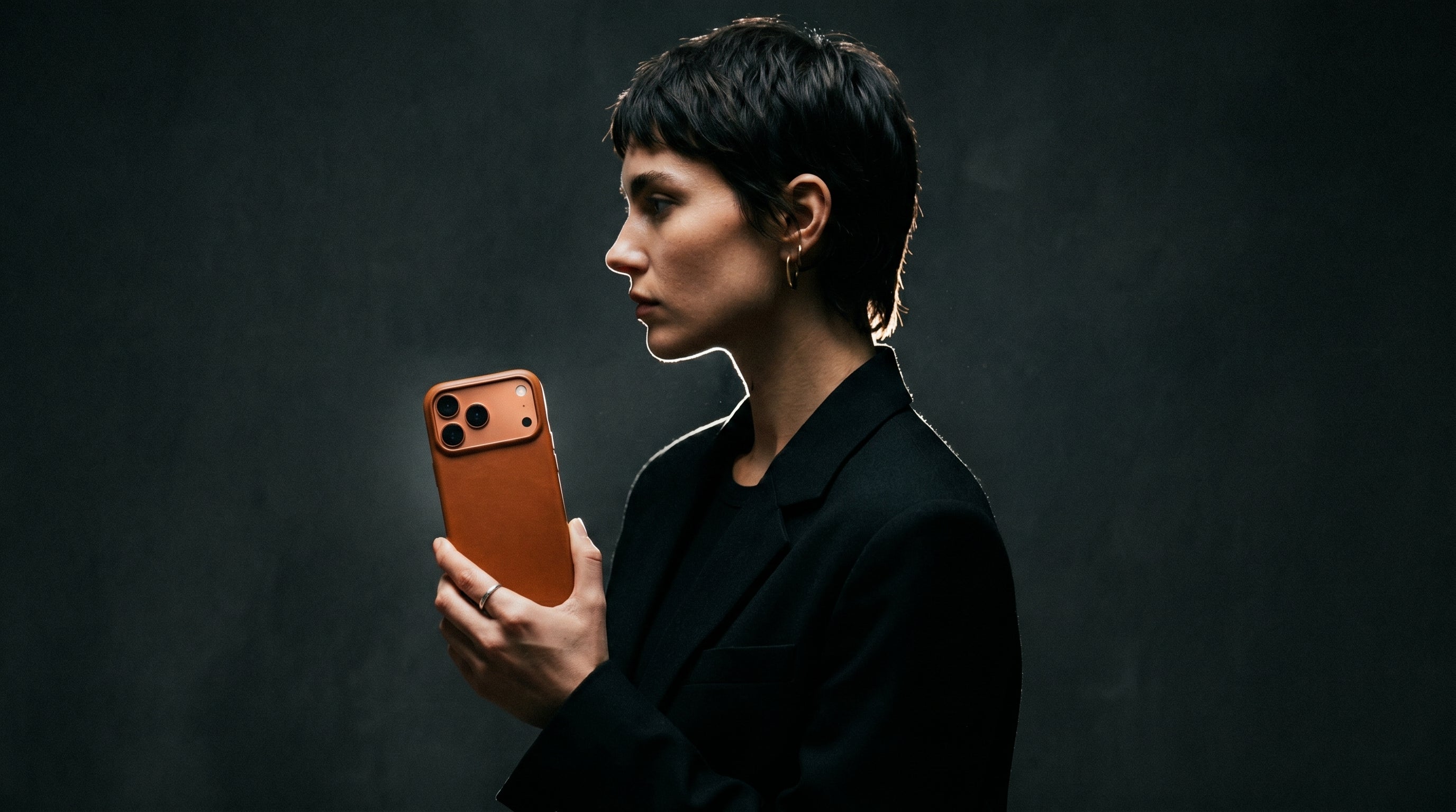 Woman holding a MUSO Barenia brown phone against a dark background